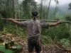 Ilustrasi peladang merentangkan sebatang bambu di tepi hutan berkabut, sesajen lemang dan telur di daun pisang