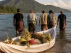 Ilustrasi perahu kecil berbalut kain putih berisi ketupat, ketan, dan buah di tepi pantai