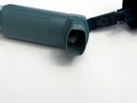 Ilustrasi inhaler asma berwarna hijau kebiruan dengan tutup terbuka di atas latar putih