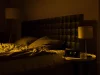 Ilustrasi kamar tidur remang dengan ranjang kusut dan jam digital menyala di nakas