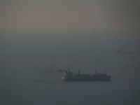 Kapal kargo berlayar di perairan Teluk yang berkabut menuju Selat Hormuz, terlihat dari Dubai