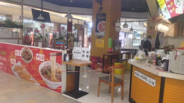 Kedai mi kecil di pusat belanja Shanghai dengan meja dipasangi garis pembatas pada masa pandemi