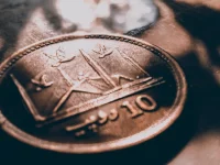 Ilustrasi koin 10 rupee Pakistan bergambar masjid dipotret dekat di bawah berkas cahaya