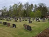 Deretan batu nisan di halaman makam Gereja Hallaryd, Swedia, dengan bangunan gereja putih