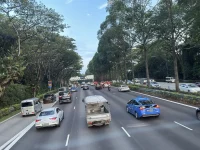 Mobil, taksi, dan truk kecil melaju di Pan Island Expressway, Singapura