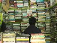 Pedagang buku bekas duduk di antara tumpukan buku di lapak Titi Gantung, Medan