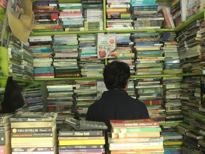 Pedagang buku bekas duduk di antara tumpukan buku di lapak Titi Gantung, Medan