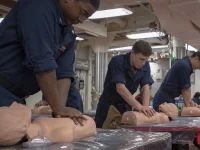 Ilustrasi pelaut Angkatan Laut AS berlatih menekan dada manekin dalam kelas CPR di kapal USS McCampbell