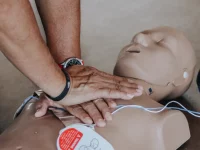 Ilustrasi sepasang tangan menekan dada manekin dalam latihan pertolongan darurat