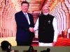 Layar besar menampilkan Narendra Modi berjabat tangan dengan Xi Jinping