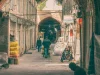 Lorong berlengkung bata di Bazar Besar Teheran, Iran, dengan orang-orang berjalan membelakangi kamera