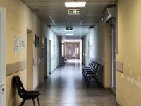 Ilustrasi lorong rumah sakit yang sepi dengan deretan kursi tunggu hitam dan pintu terbuka