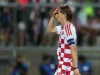 Luka Modric memegang kepala saat berjalan di lapangan dengan seragam kotak-kotak merah putih Kroasia