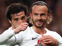 James Maddison tersenyum dirangkul rekan setim usai mencetak gol untuk Tottenham