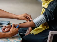 Petugas memasang manset tensimeter manual di lengan seorang perempuan di Lamu, pesisir Kenya