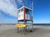 Ilustrasi menara jaga penyelamat DLRG dengan papan selamat kuning di pantai berpasir Juist, Jerman