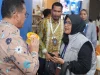Pengunjung memegang produk UMKM sementara peserta pameran menjelaskan di Paviliun Pilihan Busan