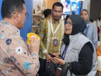 Pengunjung memegang produk UMKM sementara peserta pameran menjelaskan di Paviliun Pilihan Busan