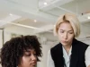 Seorang mentor perempuan memperhatikan rekan muda yang bekerja di ruang kantor