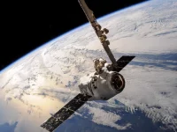 Wahana antariksa dipegang lengan robotik saat mengorbit di atas Bumi
