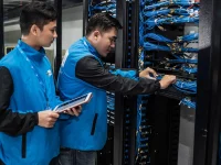 Teknisi memeriksa rak server di pusat data