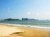 Pantai berpasir di Teluk Sanya, Hainan, dengan deretan menara hotel di kejauhan