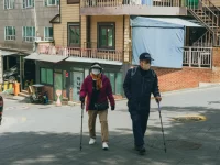 Dua lansia bertongkat berjalan di jalan menanjak permukiman di Seoul, Korea Selatan