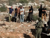 Tentara Israel berjaga saat pemukim berkumpul di kebun zaitun milik warga Palestina di Deir Abu Mishal