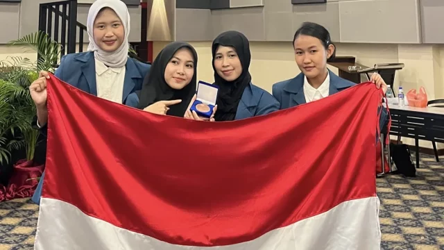 Empat mahasiswa UNAIR pembuat paving block dari limbah perikanan membentangkan bendera Merah Putih