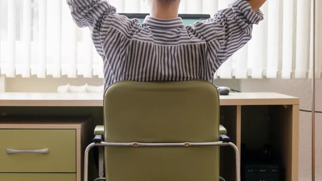 Ilustrasi pegawai kantor duduk menghadap meja dan monitor, terlihat dari belakang