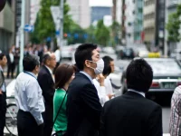 Ilustrasi: pekerja kantoran, sebagian bermasker, menunggu menyeberang di jalan kota Tokyo, Jepang