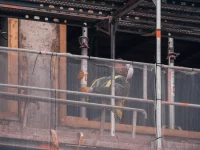 Ilustrasi pekerja konstruksi berhelm dan rompi kuning di balik perancah bangunan di Hamburg, Jerman