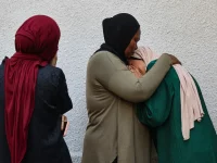 Tiga perempuan Palestina berpelukan dan berduka di dekat dinding Rumah Sakit Al-Shifa