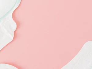 Ilustrasi beberapa pembalut putih tertata di atas latar merah muda