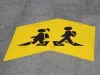 Ilustrasi marka kuning bergambar dua anak beransel penanda rute jalan kaki ke sekolah di trotoar Valencia, Spanyol