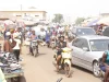 Pengendara sepeda motor memadati jalan pasar di antara mobil dan pedagang di Tamale, Ghana