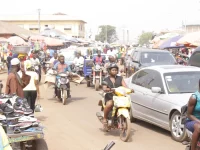 Pengendara sepeda motor memadati jalan pasar di antara mobil dan pedagang di Tamale, Ghana
