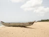 Ilustrasi perahu kano kayu tertambat di pasir Pantai Tegbi, Volta Region, Ghana