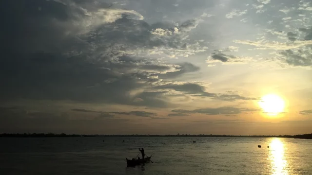Ilustrasi siluet perahu nelayan saat matahari terbenam di laut Desa Meranti Bunting, Kepulauan Meranti, Riau