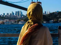 Ilustrasi perempuan berjilbab kuning dari belakang memandang Jembatan Bosphorus di Istanbul, Turki