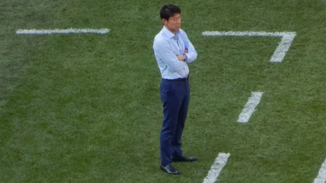 Shin Tae-yong berdiri bersedekap di pinggir lapangan saat Piala Dunia 2018