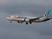 Pesawat Flydubai terbang dengan roda pendarat terbuka di bawah langit mendung