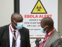 Petugas kesehatan bermasker berdiri di depan papan peringatan Ebola di Nairobi Hospital, Kenya