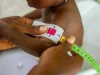 Ilustrasi petugas melingkarkan pita ukur lingkar lengan atas pada anak kecil di Nigeria