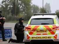 Polisi bersenjata berjaga di samping mobil patroli dekat pangkalan RAF Fairford