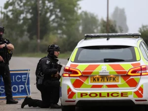 Polisi bersenjata berjaga di samping mobil patroli dekat pangkalan RAF Fairford