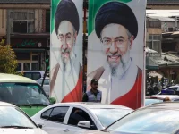 Polisi berjaga di bawah potret Pemimpin Tertinggi Iran Mojtaba Khamenei di Teheran
