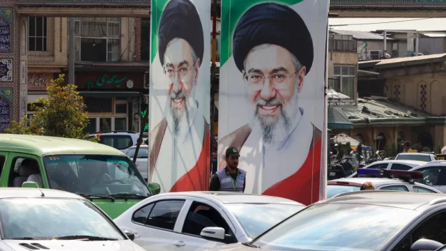 Polisi berjaga di bawah potret Pemimpin Tertinggi Iran Mojtaba Khamenei di Teheran