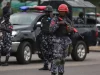 Polisi Nigeria bersenjata dan berhelm berjaga di samping mobil patroli polisi