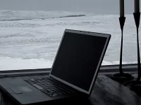 Laptop lama terbuka di meja dekat jendela